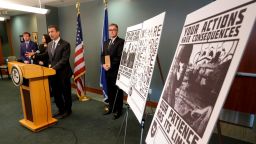 Raymond Duda, FBI Special Agent in Charge in Seattle, speaks during a news conference at a podium at left, Wednesday, Feb. 26, 2020, about charges against a group of alleged members of the neo-Nazi group Atomwaffen Division for cyber-stalking and mailing threatening communications — including the Swastika-laden posters at right — in a campaign against journalists in several cities. (AP Photo/Ted S. Warren)