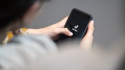 A teenager looks at a smartphone with the TikTok logo displayed.